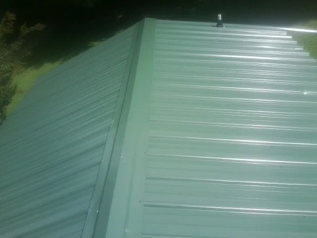 New green metal panels meeting at the ridge of a roof — Flat Roof Repair work by our crew in Brice