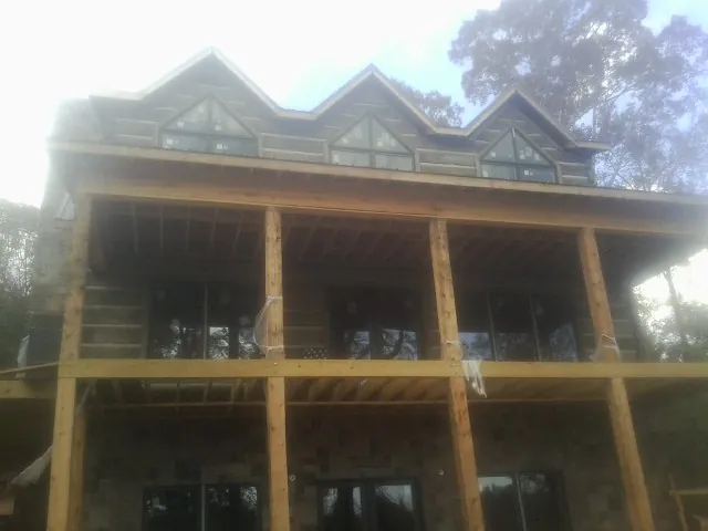 Dormers and porch framing on a large log home under construction — Roof Coating work by our crew in Brice