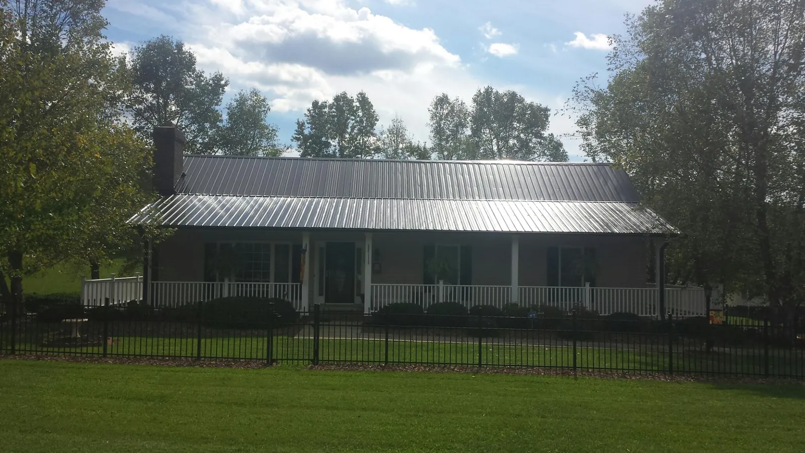 Gray metal roof on a brick ranch with a full width front porch — Gutter Guard Installation work by our crew in Brice