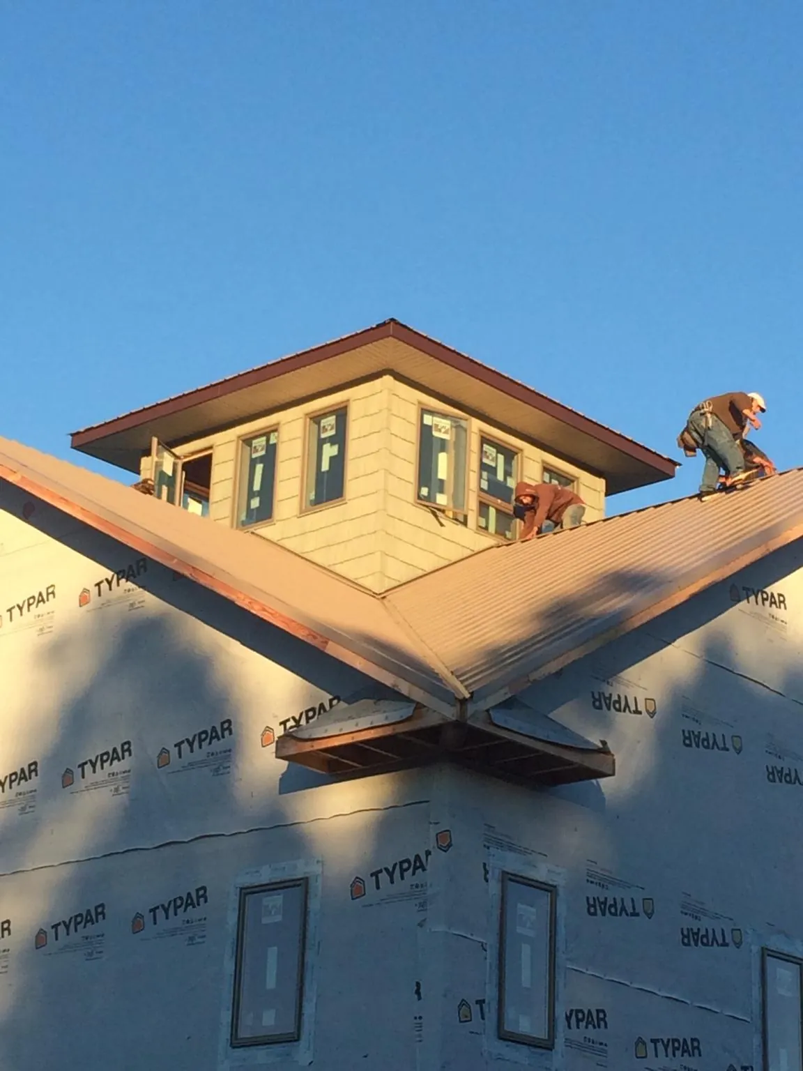 Roofers working around a rooftop cupola on a new metal roof at sunset — Roof Waterproofing in Brice by Roofing Brothers